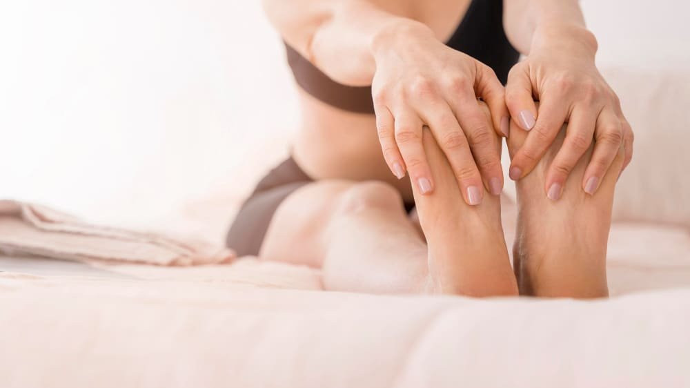 mujer masajeando pies sentada en cama mujer masajeando pies sentada en cama