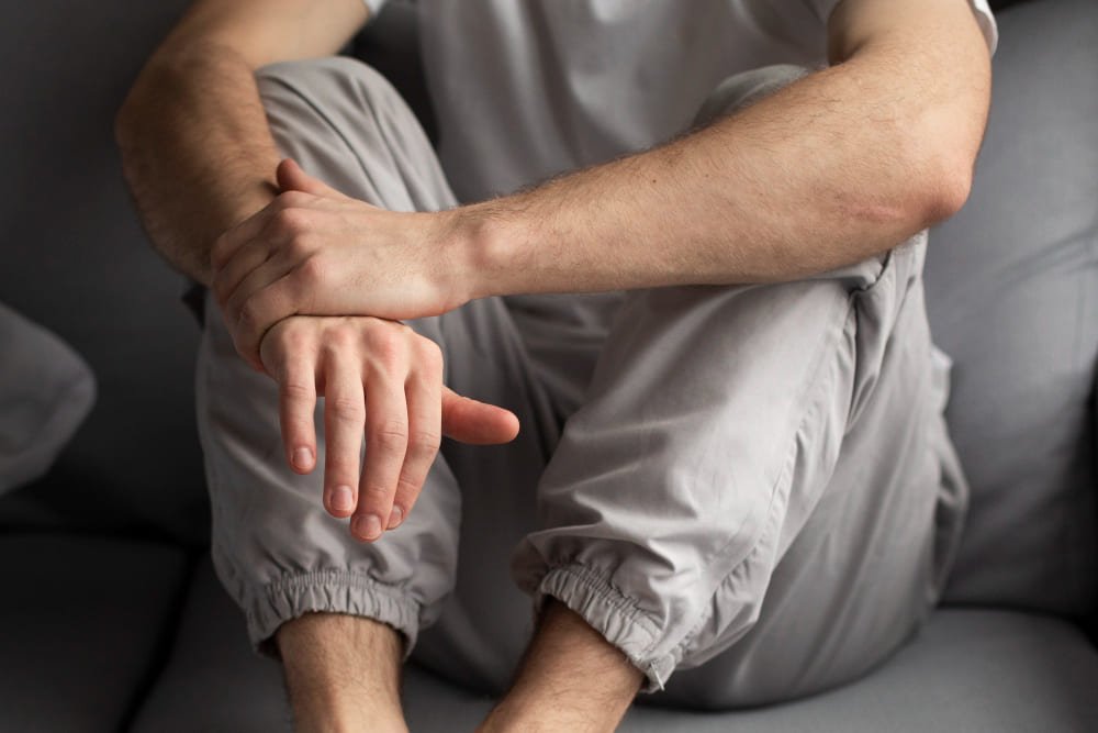persona sentada con dolor en pies y manos persona sentada con dolor en pies y manos
